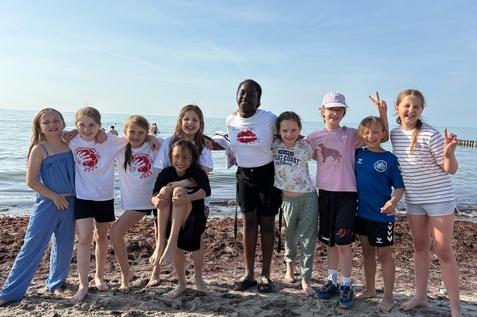 Das Handballteam der E-Jugend posiert am Strand von Warnemünde für ein Foto. Die Mädchen waren im Rahmen des Warnemünde-Cup 2025 vor Ort dabei.